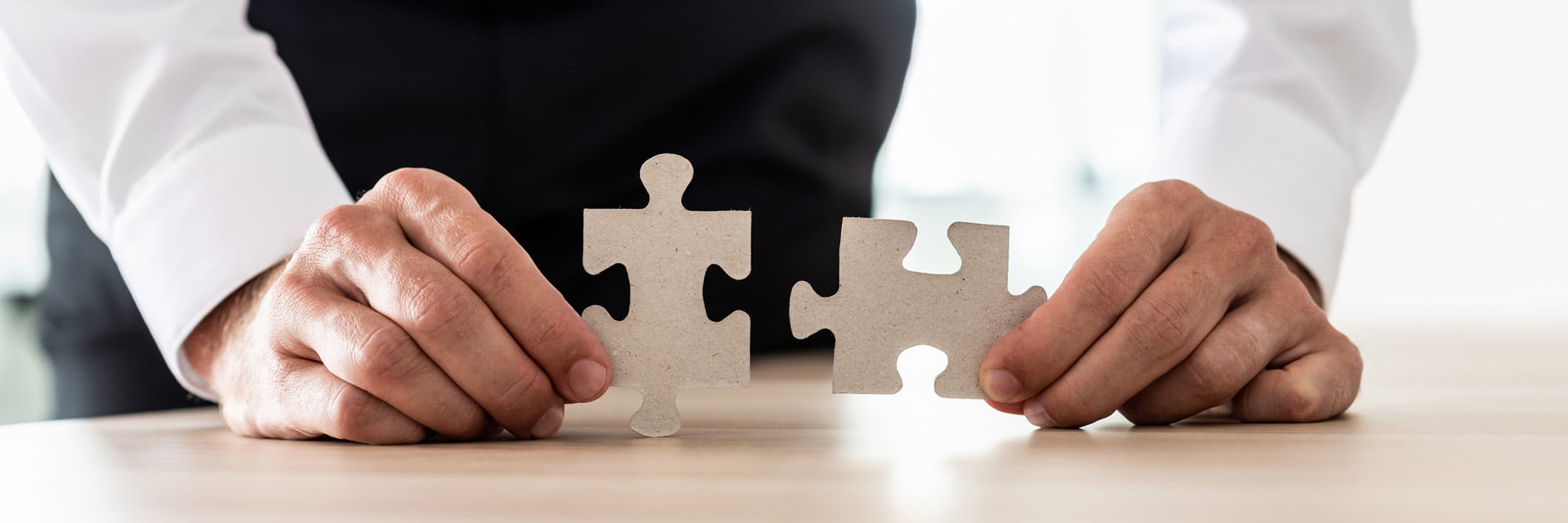 Wide view image of businessman holding two matching puzzle pieces. Conceptual of business vision and solution.